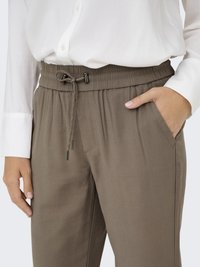 Pantalons en tissu extensible marron avec ceinture élastique et détail de cordon de serrage. Comprend des poches latérales et une coupe décontractée pour plus de confort.