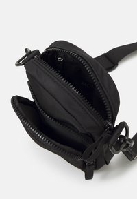 Borsa a tracolla in nylon nero con due scomparti con zip. Caratterizzata da una cinghia robusta e dettagli in metallo per una maggiore durata. Design compatto.