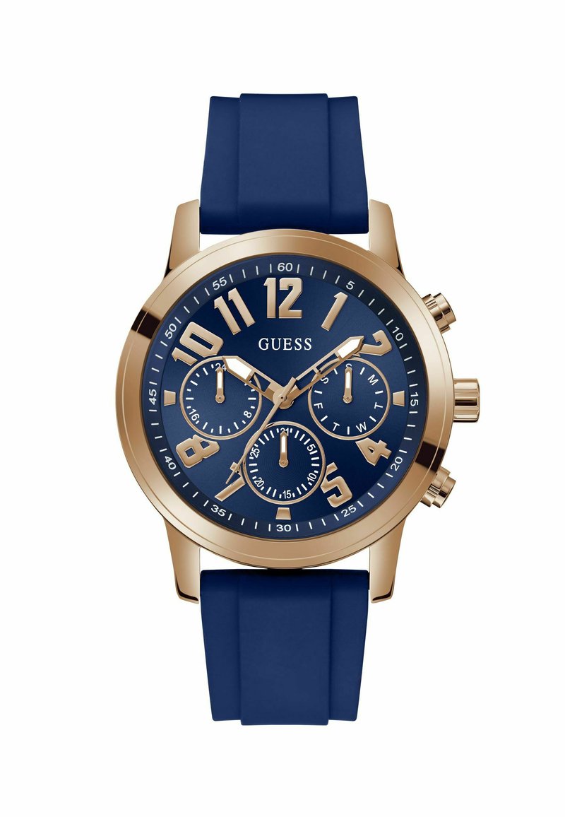Orologio Round Guess con cinturino in silicone blu navy. Cassa dorata, grandi numeri arabi dorati e tre sotto-quadranti su un quadrante blu.