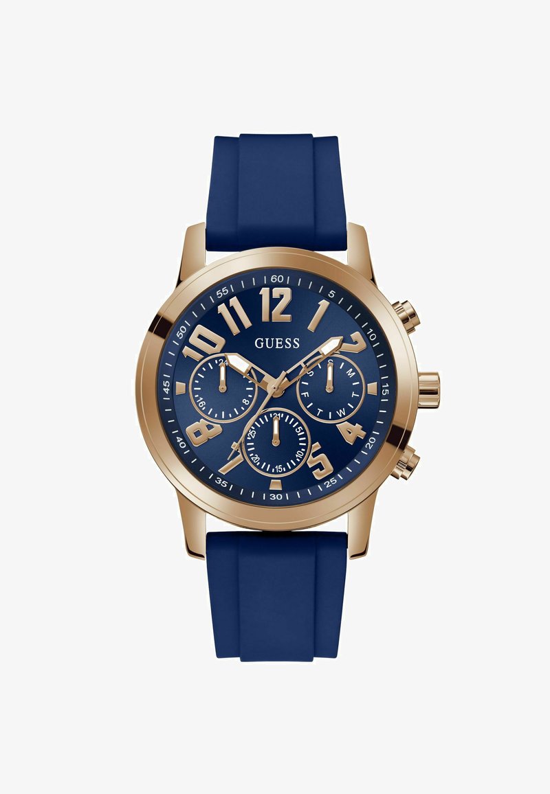 Reloj Round Guess con correa de silicona azul marino. Caja de tono dorado, grandes números arábigos dorados y tres subesferas en una esfera azul.