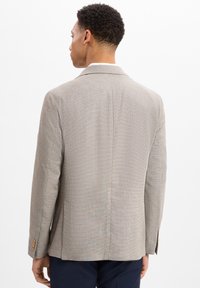 Lichtgrijze, textuur blazer met een geknipt kraag en twee achterventilaties. Voorzien van met knopen sluitende manchetten en een klassieke, op maat gemaakte ontwerp.