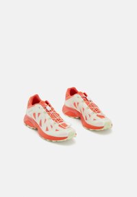 Lightweight running shoes with a predominantly white and coral color scheme, mesh upper, distinctive lacing system, and textured soles.