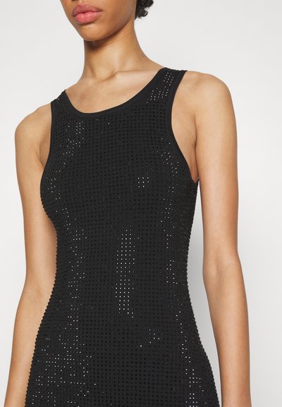 Robe noire sans manches en tissu tricoté texturé avec de petites perforations, créant un effet superposé. Encolure ronde et coupe ajustée.