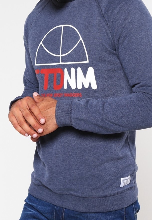 Mörkblå sweatshirt med rund halsringning, med ett vitt och rött grafiskt tryck. Ribbstickade ärmslut och kant med en liten etikett på den nedre sidan.