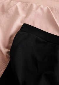 Sort bomuldsstof kombineret med lys pink, med en ribbet sort taljebånd. Glatte teksturer uden synlige mønstre eller accenter.