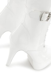 White, patent leather high-heeled boots with a pointed toe, a buckle accent, and lace-up detail along the front. Smooth, glossy finish.