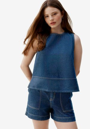 Denim sleeveless top with a loose fit, featuring dark blue fabric, a rounded neckline, and contrasting stitching. Paired with matching shorts.