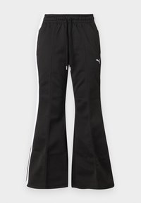 Μαύρο καμπανιστό παντελόνι φόρμας με λευκές πλαϊνές ρίγες, κορδόνι στη μέση και λογότυπο Puma στο αριστερό μηρό, πάνω σε ανοιχτό φόντο.