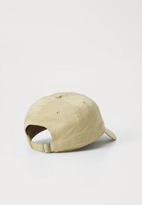 Khaki baseball cap featuring a curved brim, fabric texture, six-panel design, and adjustable strap with metal buckle at the back.