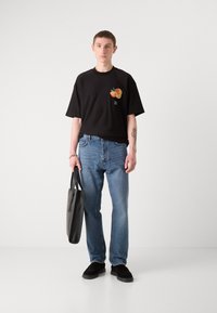 Juoda trumpa rankovėmis t-shirt su vaisių grafika. Dėvima su mėlynomis džinsomis ir juodais bateliais, laikant juodą rankinę. Lygus paviršius, laisvas kirpimas.