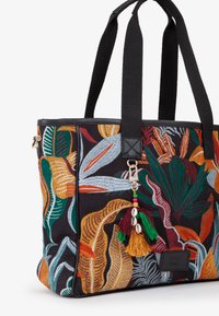 Bolsa de tela con diseños de hojas bordadas en colores vivos como naranja, verde y azul sobre un fondo negro. Asas negras y borlas decorativas.