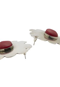 Srebrne metalowe kolczyki o kształcie kwiatu, z centralnym czerwonym kamieniem i zapięciem na wcisk. Gładka tekstura z wypolerowanym wykończeniem.