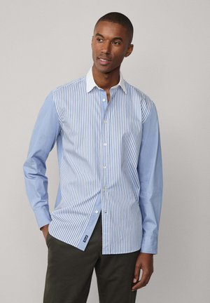 Light blue button-up shirt with vertical white stripes, long sleeves, a white collar, and a small logo tag at the hem. Smooth fabric texture.