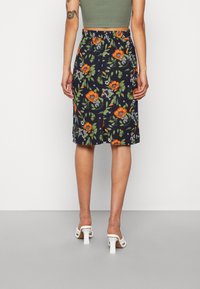 Saia midi floral com um fundo azul-marinho, flores laranjas, folhas verdes e detalhes brancos. Cintura elástica com corte reto.