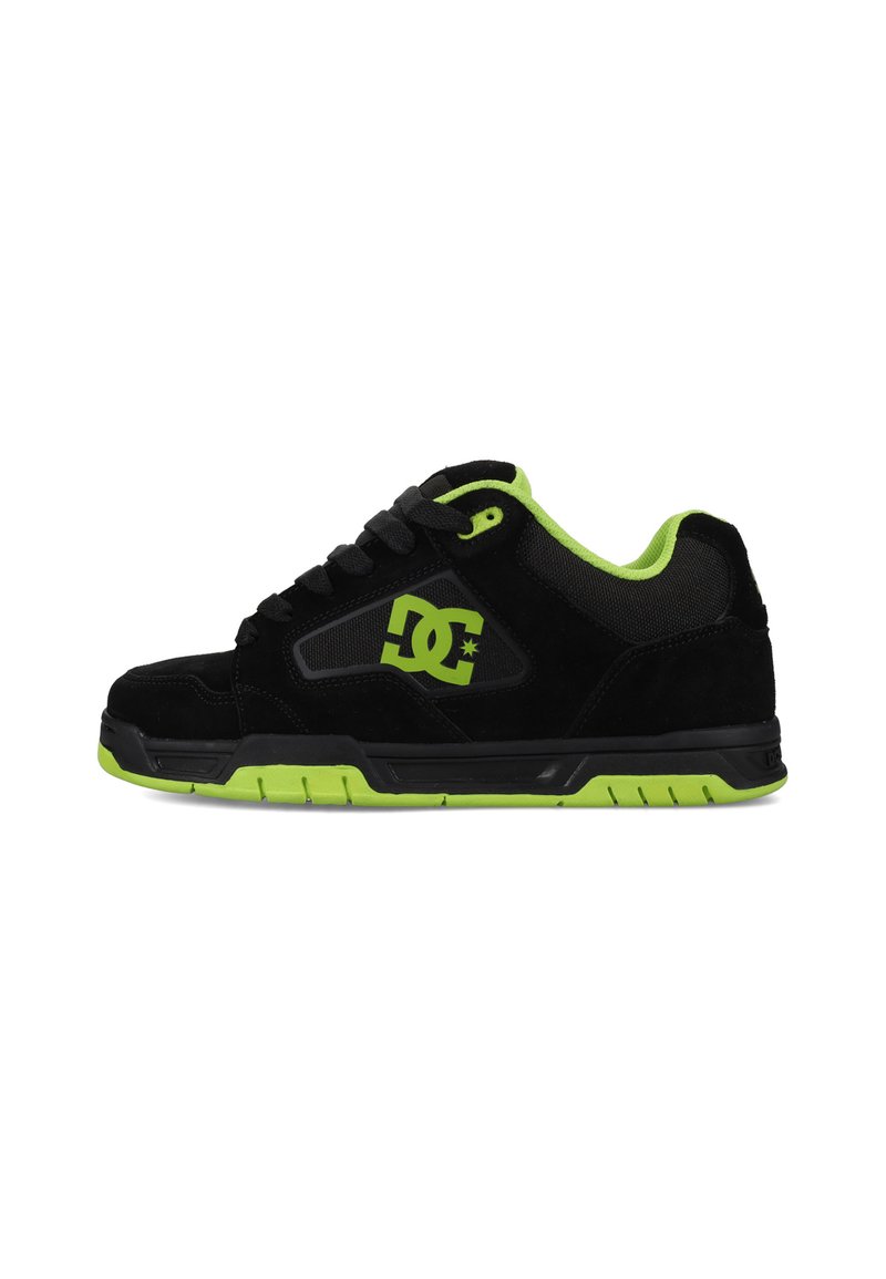 Zapatillas de ante negro con acentos en verde brillante, un cuello acolchado y una suela de goma con agarre texturizado. Logo en el lateral.