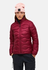 Bordeaux kleurige gewatteerde jas met een doorgestikt golfpatroon, rits aan de voorkant en hoge kraag. Draagt met zwarte broek en een roze beanie.
