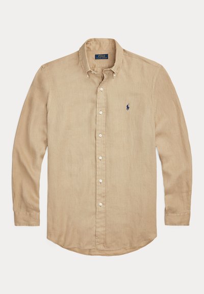 Chemise beige à manches longues en lin, dotée d'un col à boutons, de fermetures à boutons et d'un logo brodé bleu marine sur la poitrine gauche.