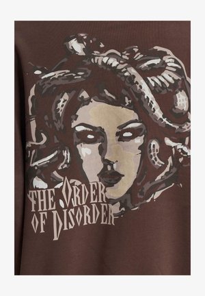 Brauner Sweatshirt mit einem Grafikdruck eines Frauenbesuchs, die Schlangen als Haare hat, begleitet von dem Text "DER ORDNUNG DES UNORDNUNG" darunter.