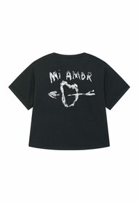 Zwart oversized t-shirt met de tekst "Mi Amor" en een hart met een pijl ontwerp in het wit op de achterkant.