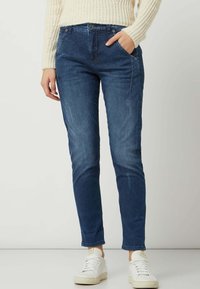 Blue denim jeans with a slim fit and whisker detailing. Features a classic five-pocket design and a slight fade for texture.