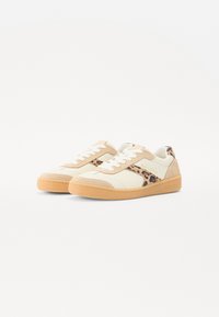 Beige és krémszínű sportcipők leopárdmintás részletekkel, texturált velúr anyagból készült, gumitalpakkal és kontrasztos rágógumi talppal.