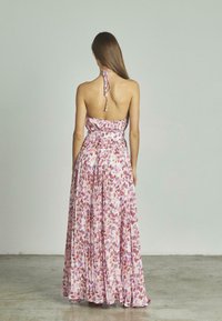 Vestido maxi de tela rosa con un patrón floral en tonos de rosa y púrpura. Diseño de cuello halter con un torso ajustado y falda fluida.