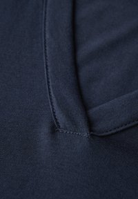 Tessuto blu navy con una texture liscia, dotato di un colletto piatto e dettagli di cucitura discreti vicino al collo.