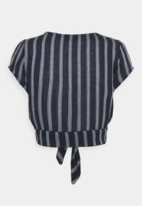 Top corto a maniche corte blu navy con strisce verticali bianche. Caratterizzato da un collo rotondo e un dettaglio legato sul retro. Tessuto leggero.