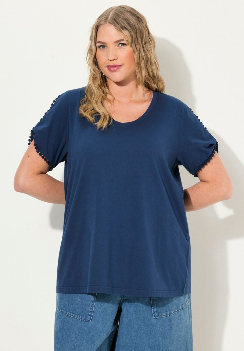 Námořnická modrá tričko s V-výstřihem, s krátkými rukávy zdobenými třásněmi. Vyrobeno z měkké látky, s volným střihem.