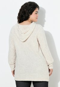 Felpa con cappuccio color beige chiaro con maniche lunghe, vestibilità comoda e tessuto strutturato. Presenta una rifinitura a coste intorno ai polsini e all'orlo.