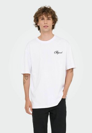 Vit bomull t-shirt med korta ärmar, rund hals och svart "Original"-text på vänster bröst. Matchat med svarta denimbyxor.