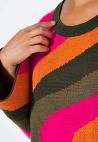 Maglione lavorato a maglia con audaci motivi a righe in rosa, arancione e verde. Collo rotondo con tessuto testurizzato e vestibilità ampia.