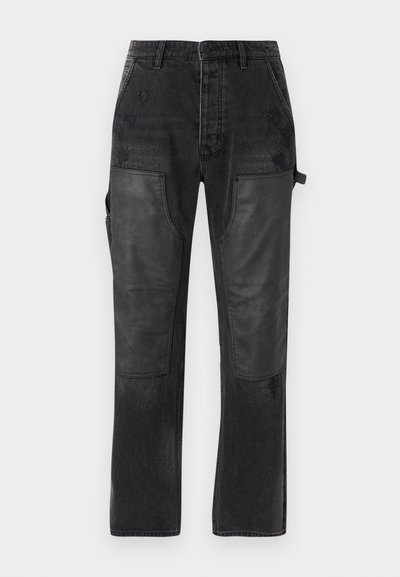 Mustadest denimist püksid, millel on kontrastsed mustad nahast paneelid, sirge jala disain ja peened kulumise üksikasjad kangal.