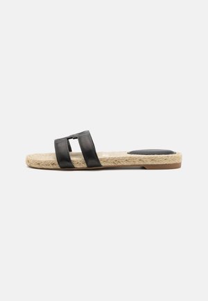 Flad slip-on sandal med vævet beige sål og to sorte læderremme over toppen samt en sort hælpude.