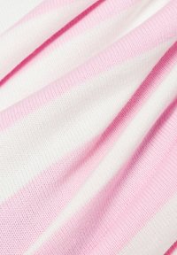 Tissu rayé aux couleurs rose et blanche avec un motif en tricot texturé, montrant des plis et des drapés.