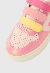 Rosa og gul barne-sneaker med borrelås, skinnoverdel, perforert tå og en teksturert gummisåle.