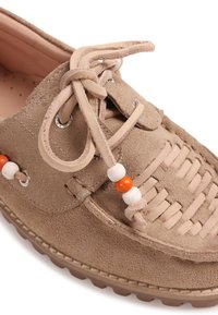 Mocassin en daim marron clair avec détail tissé à l'avant, lacets en cuir ornés de perles en bois blanches et orange, et semelle en caoutchouc cousue.