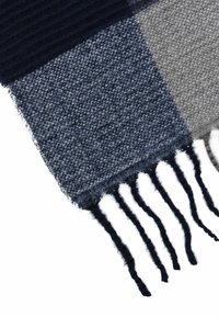Wool scarf featuring a checked pattern in navy and gray, with fringed edges and a soft texture. Rectangular shape and warm design.
