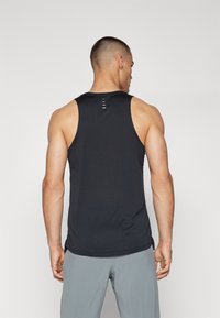 Débardeur de sport noir avec une texture lisse, proposant des coutures minimalistes et un ourlet arrondi. Conçu pour le confort lors des entraînements.