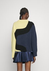 Strickpullover mit einem Farbblockdesign in Gelb, Schwarz und Marineblau; lockere Passform, runder Halsausschnitt und gerippte Bündchen.