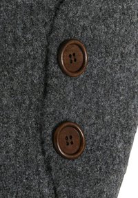 Sivi vuneni materijal s teksturiranom površinom, sa dva okrugla smeđa dugmeta s četiri rupe svako, smještena s lijeve strane.