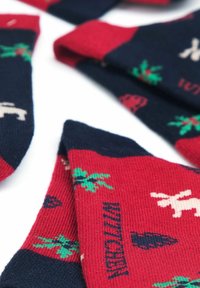 Calze rosse e blu navy con motivi a tema festivo, inclusi conigli e alberi, realizzate in tessuto lavorato a maglia. Presentano polsini a coste e superficie testurizzata.