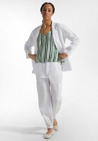 Luźne, białe lniane spodnie i dopasowana, lekka długa kurtka na cienkim, zielono-białym paskowanym topie. Tkanina o strukturze na całej powierzchni.