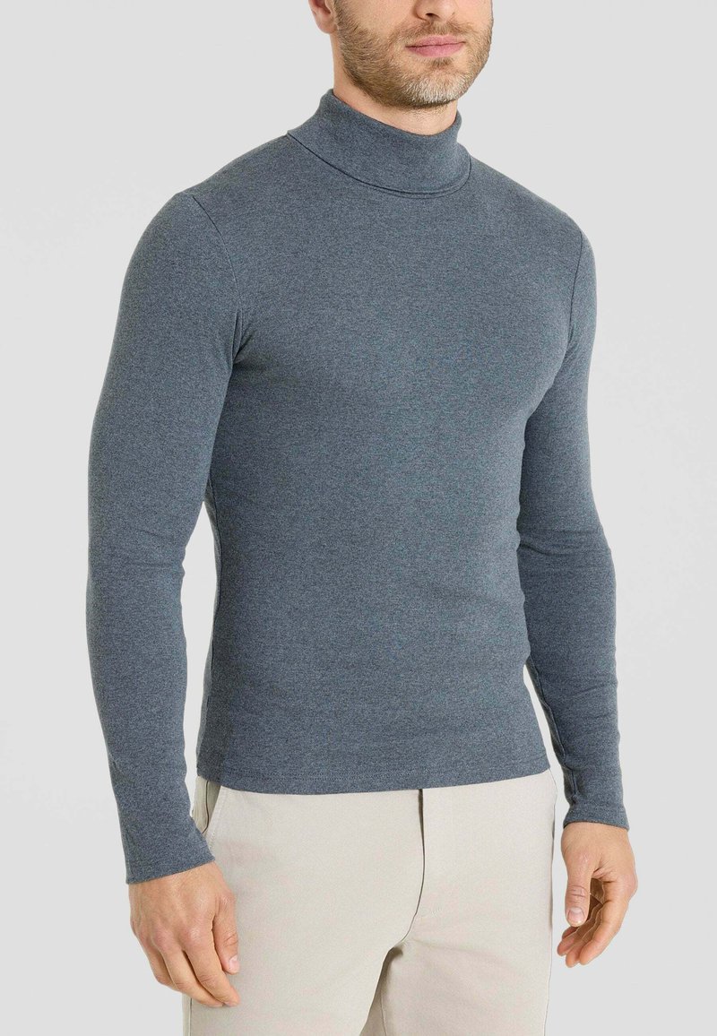 Maglione grigio con collo alto e maniche lunghe, realizzato in materiale morbido. Design aderente con una texture liscia. Colore semplice e uniforme.