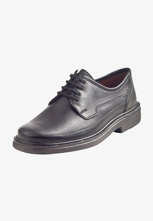 Zwarte leren veterschoen met een gladde afwerking, ronde neus, contrasterende stiksels en een dikke rubberen zool. Inclusief zijpaneel details.