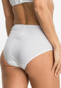 Woman wearing high-waisted white underwear with textured fabric, shown from the lower back to mid-thigh, against a plain background.