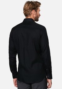 Zwarte lange mouwen knoopsluiting shirt met een gladde textuur, taillerend ontwerp, standaard kraag en manchetten. Achteraanzicht toont een slimfit snit.