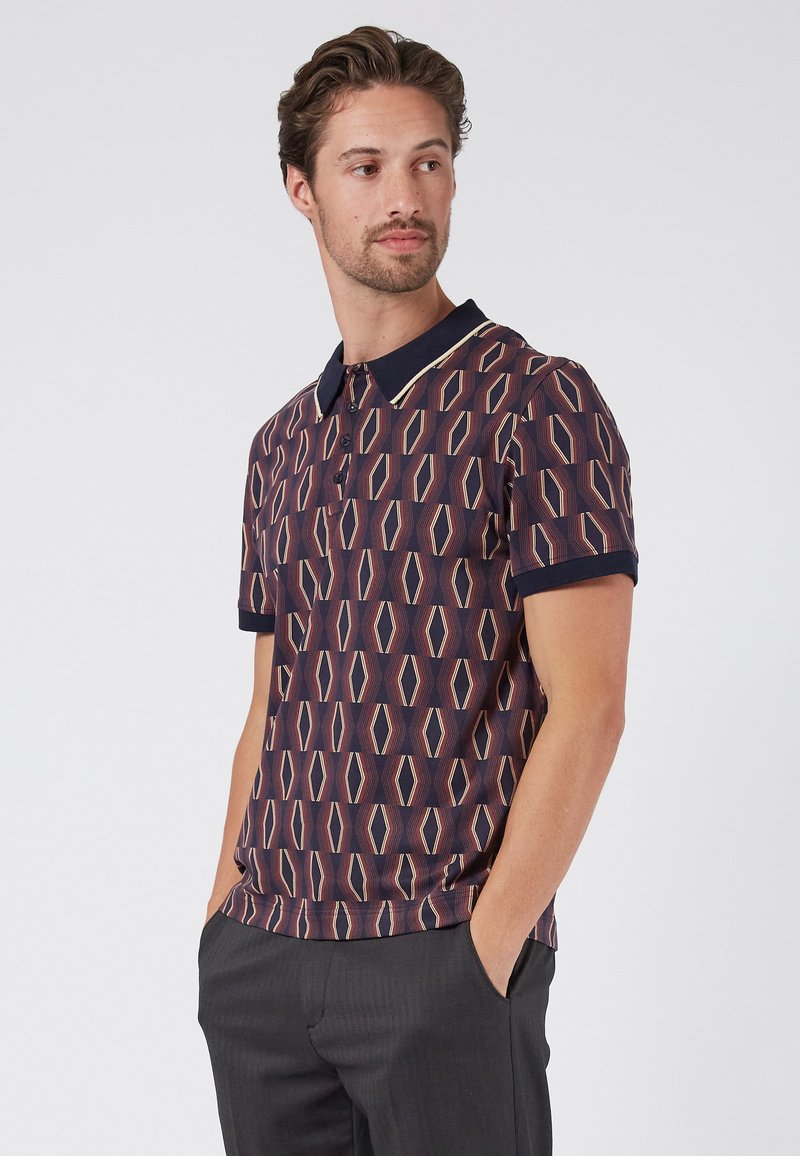 Polo de manga corta hecho de tela estampada con formas de diamante en color burdeos, crema y azul marino, con un cuello en contraste.