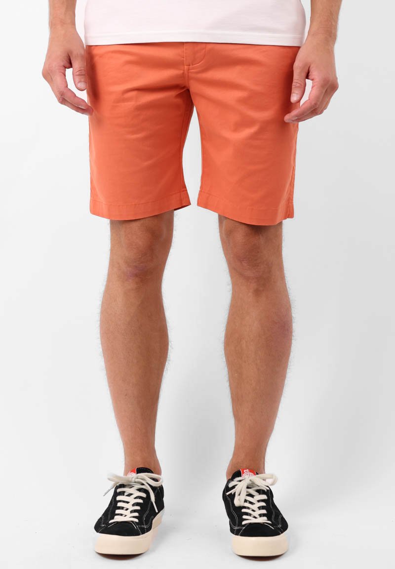 Shorts en coton orange avec un devant plat, des poches latérales et arrière, et un ourlet propre, associés à des baskets noires.