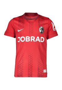 Maglia da calcio rossa con collo rotondo, maniche corte e un motivo a gradiente di triangoli. Presenta il logo "JOBRAD" e l'emblema della squadra sul petto.